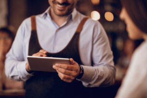 Close-up of waiter with digital tablet taking order from a guest