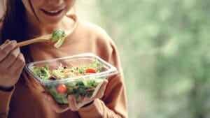 Closeup woman eating healthy food salad, focus on salad and fork